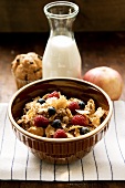 Berry muesli with cereal flakes in a bowl, milk behind