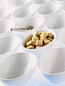 Brown sugar cubes in a bowl among empty bowls
