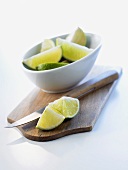 Chopping board, kitchen knife and lime wedges