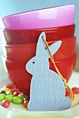Blue felt bunny in front of red bowls