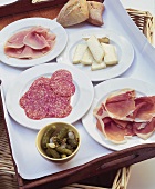 Gherkins, ham, salami, Camembert and bread rolls on tray