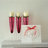 Three white roses in pink champagne glasses