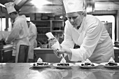 Female chef putting cream topping onto desserts