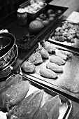 Raw chicken pieces on baking trays in kitchen