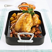 Roast chicken in roasting dish with potatoes and sausages