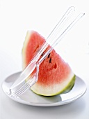 Ein Stück Wassermelone auf einem Teller mit Plastikbesteck