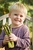 Small boy with green asparagus in his hands