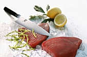 Two tuna steaks on ice with knife