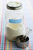 Flour in screw-top jar with measuring cups