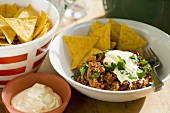 Chili con carne with sour cream and corn chips