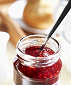 A jar of raspberry jam with spoon