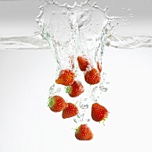 Frische Erdbeeren fallen ins Wasser