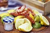 Fresh shrimps, lemons and salt on wooden board