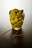 Green olives and olive oil in a glass