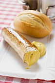 Sausage (partly eaten) with mustard and baguette roll