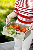 Woman holding crate of fresh tomatoes