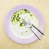 Remains of spinach on plate with knife and fork