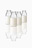 Vier Milchflaschen auf spiegelnder Fläche
