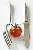 Cherry tomato between knife and fork