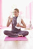 Woman in lotus position holding bottle of water