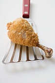 Breaded chicken leg on spatula