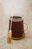 A glass of black tea with sugar swizzle stick