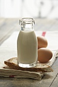 Flasche Milch, Brotscheibe und Eier auf Geschirrtuch