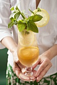 Woman holding a glass of iced tea with lemon and mint