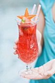 Woman holding fruity strawberry drink out of doors