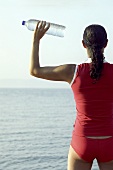 Young woman on beach with bottle of water in her hand