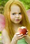 Young girl dressed as fairy with an apple