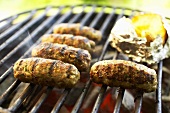 Cevapcici with baked potato on barbecue (close-up)
