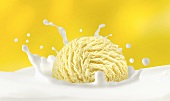 A scoop of vanilla ice cream falling into milk