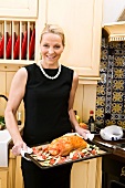 Woman dressed for dinner party holding duck on baking tray