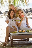 Mutter und Töchter essen Wassermelone am Strand