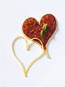 Zwei Herzen aus Spaghetti, eines gefüllt mit Tomatensauce