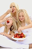 Mother and daughters eating fresh strawberries