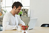 Man using laptop on kitchen table