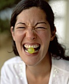 Young woman with a grape between her teeth