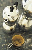 Espresso in glass cup in front of espresso pots