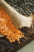 Red and black lentils with jute on wooden background