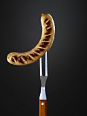 A sausage speared on a carving fork