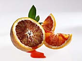Half a blood orange with juice and wedges of blood orange