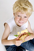 Blond boy with salami and cheese sandwich