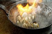 Flambéing clams in a frying pan