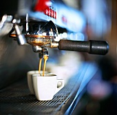 Espresso fliesst aus der Maschine in zwei Tassen