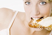 Woman biting into pretzel stick with sunflower seeds