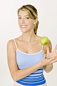Junge Frau spielt mit einem Apfel