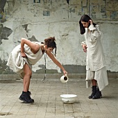 Two women, one pouring water into a bowl