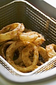 Deep-fried onion rings in basket of deep fat fryer